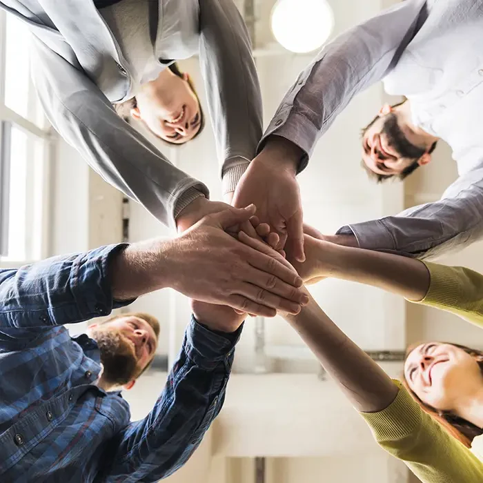 Mãos de uma equipe unidas ao centro